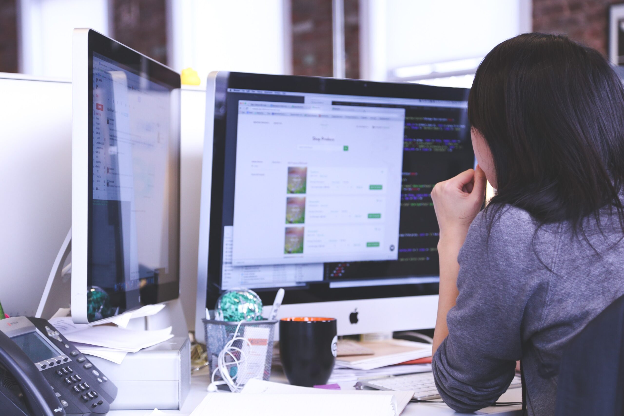 A person in front of multiple monitors at work.